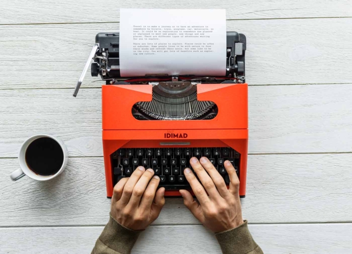 persona trabajando en maquina de escribir antigua con un café