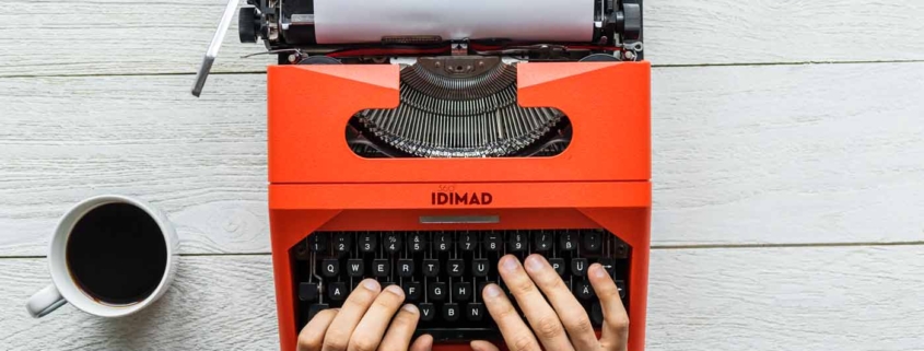 persona trabajando en maquina de escribir antigua con un café